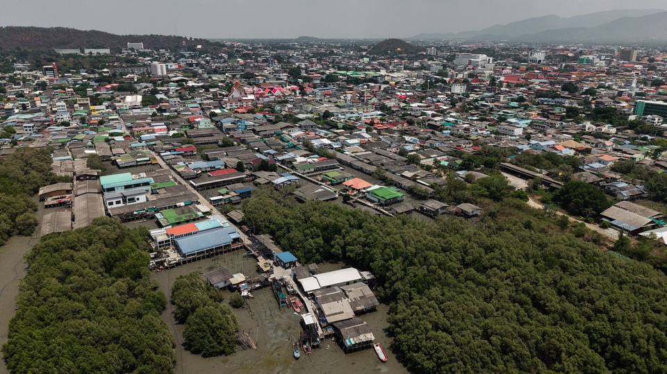 รับถ่ายวีดีโอทางอากาศ แสดงภาพรวมของชุมชนริมชายฝั่งทะเล มีอาคารบ้านเรือนหนาแน่น ต้นไม้สีเขียวขจีบริเวณชายเลน พร้อมให้บริการถ่ายโดรน รับถ่ายวีดีโอ เชียงใหม่ กรุงเทพฯ ตัดต่อวิดีโอ tiktok ทำวีดีโอ